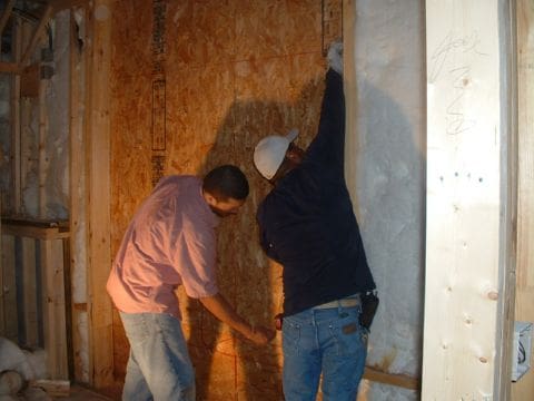 Two men working on a wall in the process of being built.