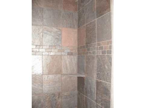 A tiled shower with the door open.