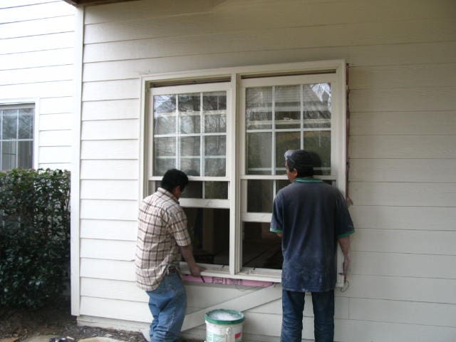Two men are painting the windows of a house.