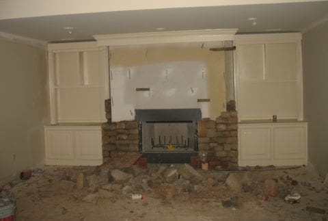 A fireplace in the middle of a room with rubble around it.