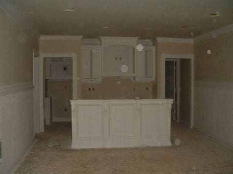A kitchen with white cabinets and walls in the middle of it.